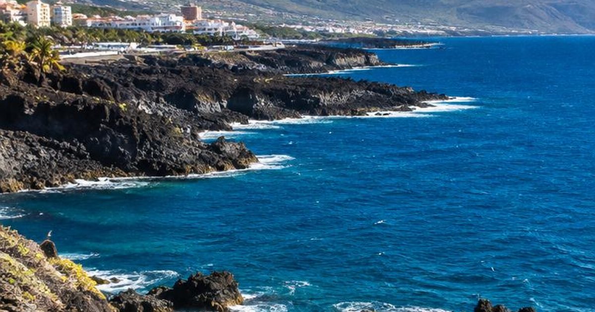 Rocky volcanic coastline, blue Atlantic water and a high mountain inland