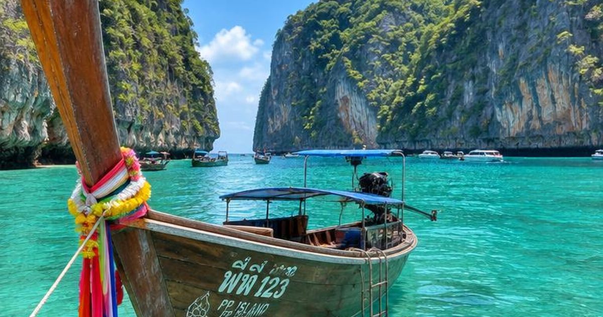 A long-tail boat in clear turquoise water between steep limestone cliffs