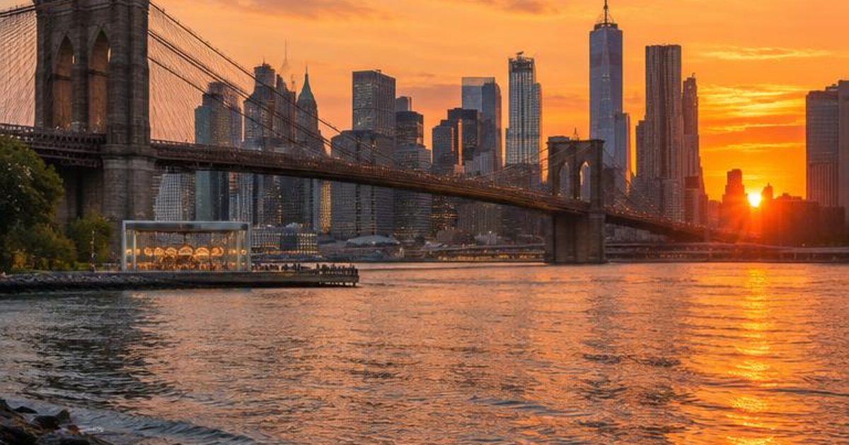 Waterfront view toward the Manhattan skyline and a suspension bridge at sunset